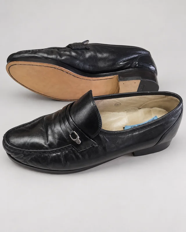 Pair of black leather loafers, with one turned over to show the renewed sole