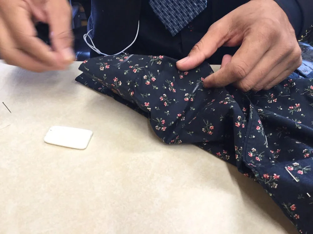 Hand stitching a floral garment at Miracle Cleaners